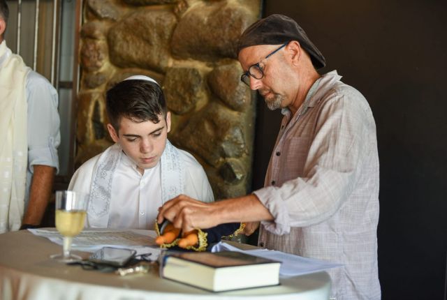 גיל קופטש וילד בר המצווה קוראים בתורה ליד קיר אבן